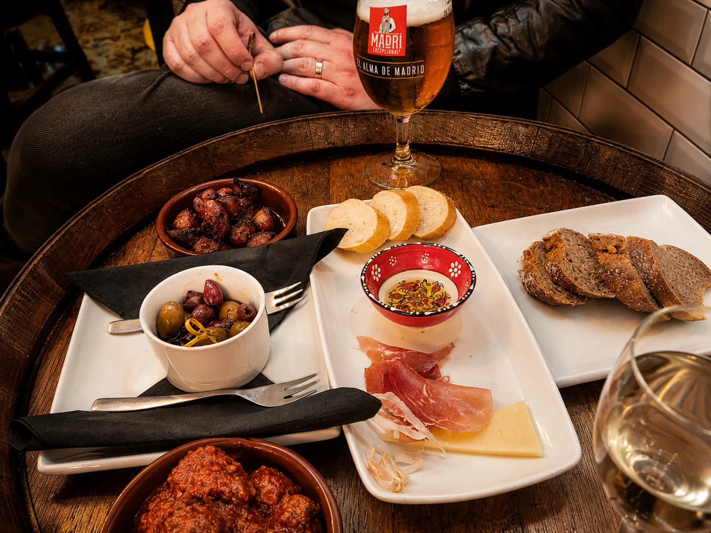 A glass of Spanish beer with a sharing table of tapas
